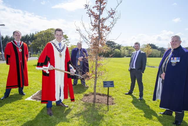 The Mayor, Cllr Peter Johnston, plants a tree at Larne Town Park to mark the centenary of Northern Ireland as council colleagues look on.
