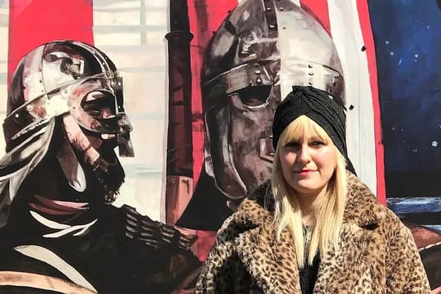 Kim in front of a Viking themed public artwork panel commissioned by Mid and East Antrim Borough Council and Larne Renovation Generation. The original painting was photographed by Bernie McAllister of Argyll Images.