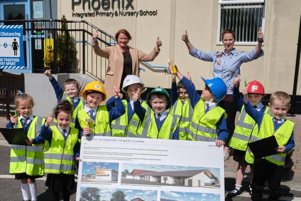 Pupils from Phoenix Integrated Nursery and Primary School along with Mrs Heather Watson (Principal) and Mrs. Liz Simpson (Chair of Board of Governors) examine the plans for a new school building on the current site.
