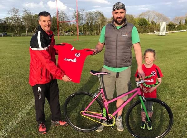 Andy McCrea (left) receiving new training and playing tops from Andrew Hassard of Mango Bikes, and his daughter Heidi.