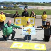 Pictured at Ballycastle Seafront, with the striking Fairhead in the background, are Members of both GAA Clubs - the event organisers, Martin McAuley, Úna Kelly, Cíara and Caoimhe McShane and James Mulholland. Accepting the cheque on behalf of the local Marie Curie group are Winnie McGarry, Sharon McClean and Briege McGarry