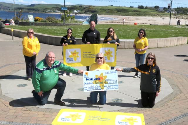 Pictured at Ballycastle Seafront, with the striking Fairhead in the background, are Members of both GAA Clubs - the event organisers, Martin McAuley, Úna Kelly, Cíara and Caoimhe McShane and James Mulholland. Accepting the cheque on behalf of the local Marie Curie group are Winnie McGarry, Sharon McClean and Briege McGarry