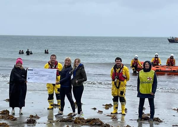 Some of Larne RNLI’s volunteer crew and members of the fundraising team are presented with a cheque for £1,016 by the Chilli Dippers at Ballygally beach