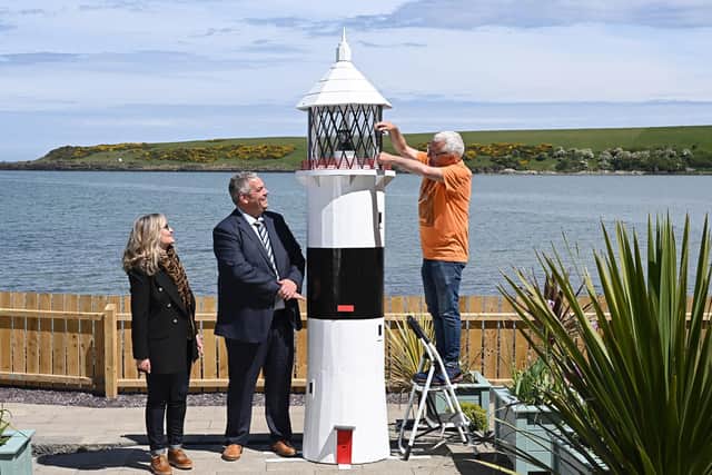 Looking on as charity volunteer Sam McCullough makes a final adjustment to the lighthouse are David Savage, governor Maghaberry Prison and Dawn McConnell, founder of the Hope House charity. Picture: Michael Cooper