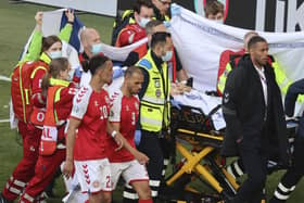 Denmark’s Christian Eriksen (hidden) leaving the pitch on Saturday after life-saving pitchside treatment. Pic by PA.