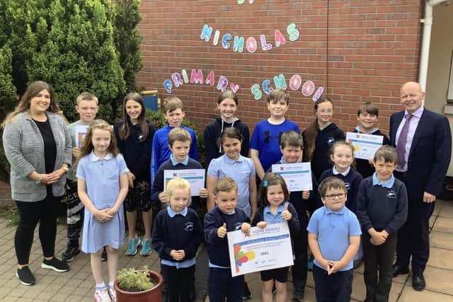 St. Nicholas' PS in Carrickfergus has been recognised with the Digital Schools Award for Northern Ireland.  Pictured celebrating the achievement are Laura Moloney, ICT co-ordinator and principal Mr Kieran Austin with P1, P4 and P7 pupils.