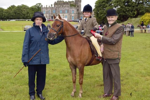 Six-year-old Kelly Taggart, Irvinestown, winner of the First Ridden Class at Enniskillen Horse and Pony Show, receiving her rosette from the judges, Mary Doonen, Athlone and George O'Malley, Longford.