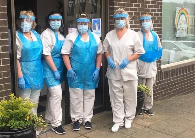 At the height of the pandemic are staff of Hebron House, Markethill,  wearing scrubs donated by Alexander’s of Markethill. Mildred is in white without an apron.