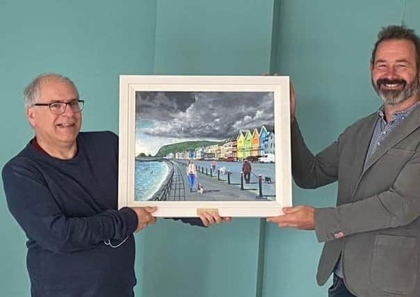 Presenting Rev Ian Carton with a painting of Whitehead seafront by artist Ken Stewart is Martin Clarke, acting chairman of Whitehead Community Association.