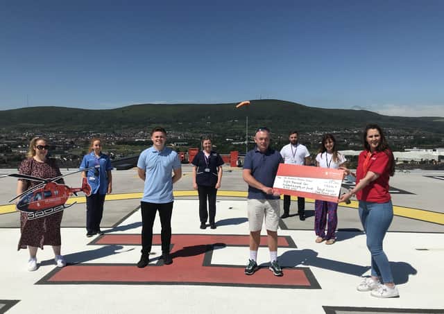 Patrick presents Grace Williams, Area Fundraising Manager for Air Ambulance NI with his donation, surrounded by his colleagues from RVH who participated in the walking challenge