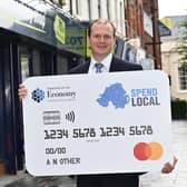 Economy Minister Gordon Lyons with the £100 voucher logo