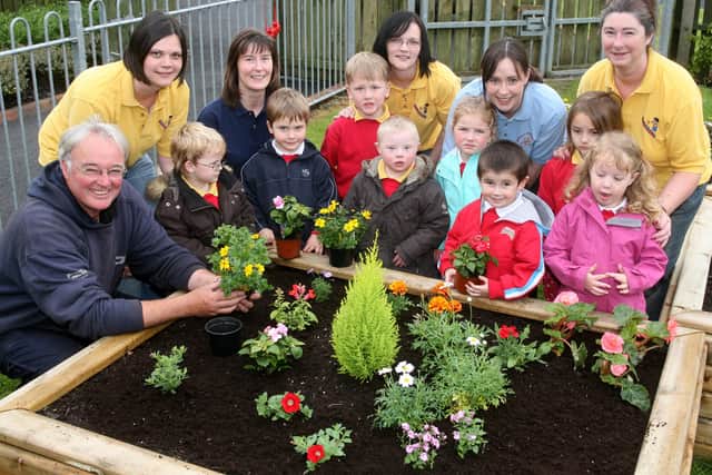 Frank McCook of Slemish Market Garden with children from Gracehill PS nursery unit and Stepping Stones Playgroup planting flowers as part of a Growing Together Project, funded by the Intergrated Schools Project. Included are Sharon Young, Linda Warwick, Evelyn Swann, Christina Hart and Jean Herbison. BT21-202AC