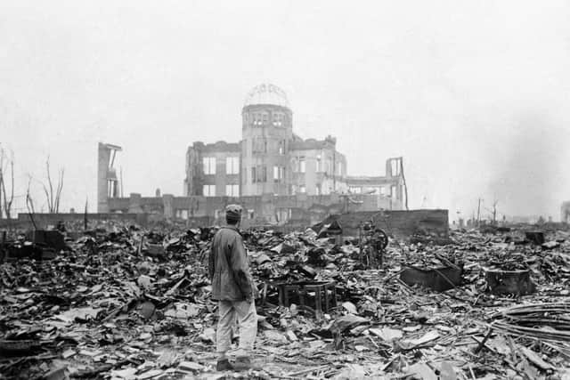 In this September 8, 1945 file photo, an allied correspondent stands in the rubble in front of the shell of a building that once was a exhibition center and government office  in Hiroshima, Japan, a month after the first atomic bomb ever used in warfare was dropped by the US on August, 6, 1945. (AP Photo/Stanley Troutman, File)