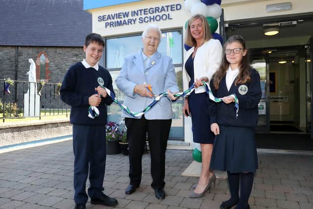 Seaview Primary School in Glenarm transfers to controlled integrated status. Cutting the ribbon on day one is (left) Baroness May Blood of the Integrated Education Fund (IEF) and Joanne Mathews, chair of the board of governors. Primary 7 pupils Hayden Rhodes and Michaela McAllister help with the ceremony. Photograph by Declan Roughan/Press Eye.