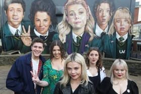The 'Derry Girls' next to a mural in the city