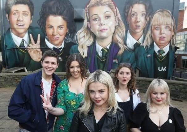 The 'Derry Girls' next to a mural in the city