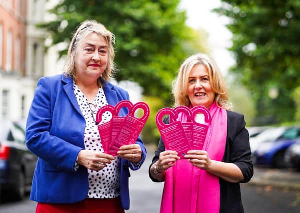 Katherine Robertson (left) and Paula Murray (right) with waterproof cards that hang in the shower to give instructions on the best procedure for breast self-examination