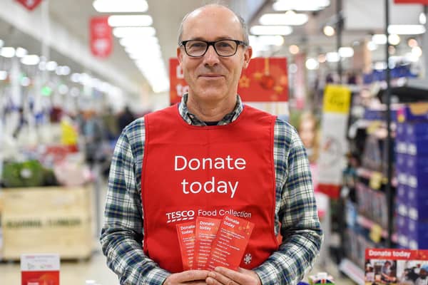 A Tesco volunteer holding a shopping list guide for donations at the launch of the Tesco Food Collection