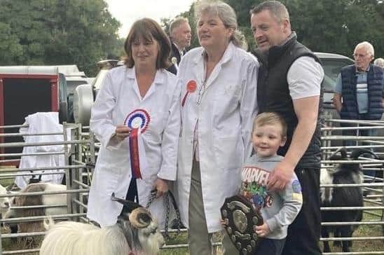 Connbrook Dave, a pygmy goat from a herd in Lisburn recently won male champion and show champion at the Castlewellan Show.  The awardwinning goat was also crowed Show Champion Male and Reserve Show champion at the Clogher Show. Pictured are judge Hilary Breakell, sponsor Anthony Kelly with his son and Margaret showing Connbrook Dave