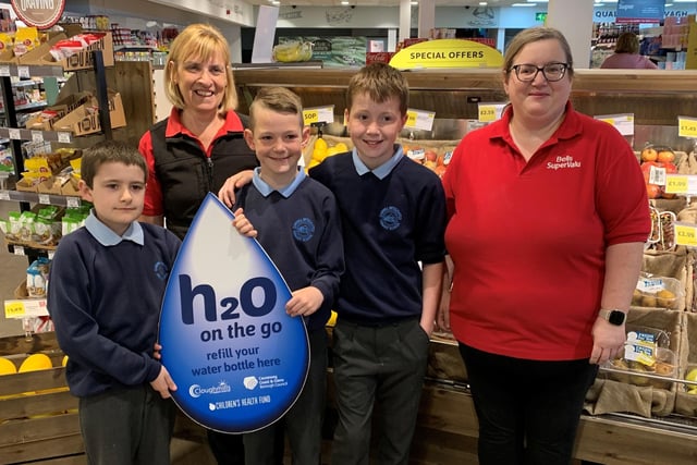 Staff from Bell’s Super-Valu pictured with pupils from Carhill Integrated Primary School after signing up to the H20 On The Go scheme