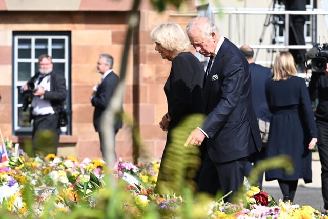 King Charles III and the Queen Consort look at floral tributes as they arrive at Hillsborough Castle, Co Down. Picture date: Tuesday September 13, 2022.