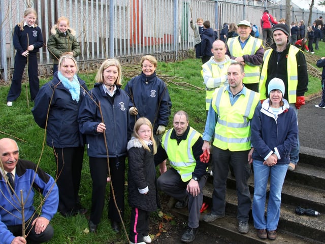 Members of Harryville Partnership Initiative, who helped pupils from Harryville Primary School to plant willow trees along the school’s perimeter fence, are seen here with Frank Jackson (left) of Ballymena Ecos Centre school staff and pupils. BT46-115JC