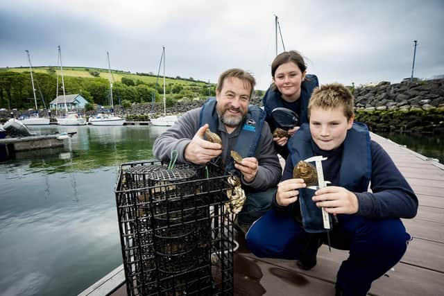 Cliodhna Matthews and Rory Tweed from Seaview Primary School join Dr  Dave Wall, senior marine conservation officer with Ulster Wildlife, at the launch of the new native oyster nursery at Glenarm Marina.