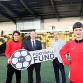 Communities Minister Gordon Lyons pictured at Blanchflower Stadium with Graham Fitzgerald, Chief Operating Officer at the Irish Football Association, and Jake and Leon from Ashfield Boys' High School, making the announcement of funding including the Parker Avenue 3G Pitch Project in Portrush.