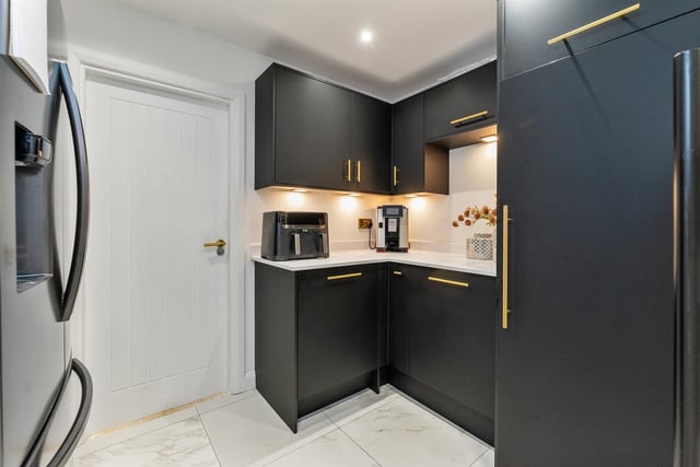 Utility room with range of fitted high and low level storage units with solid quartz work surface.  There is space for an American style fridge freezer, integrated Bosch dishwasher, plumbing and space for a washing machine, and space for a tumble dryer.