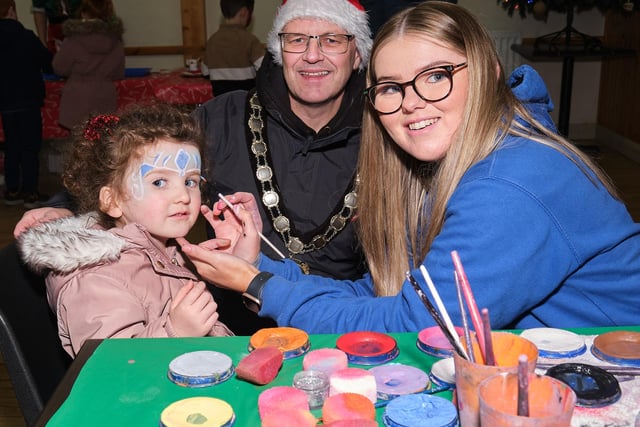 Chair of Mid Ulster District Council, Councillor Dominic Molloy, watches a face-painting transformation take place.