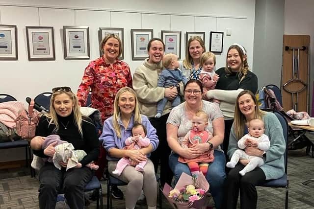 Breastfeeding Peer Support Volunteer Laura Nokes pictured at Lisburn’s Library with a class of mums and tots receives a congratulatory bouquet as she prepares for a career in paediatric nursing. Pic credit: SEHSCT