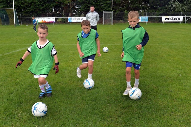 Boys who attended the Healthy Kidz Summer Camp trying out their dribbling skills during a soccer coaching session with coach, Conor Larkin, back. PT31-216.