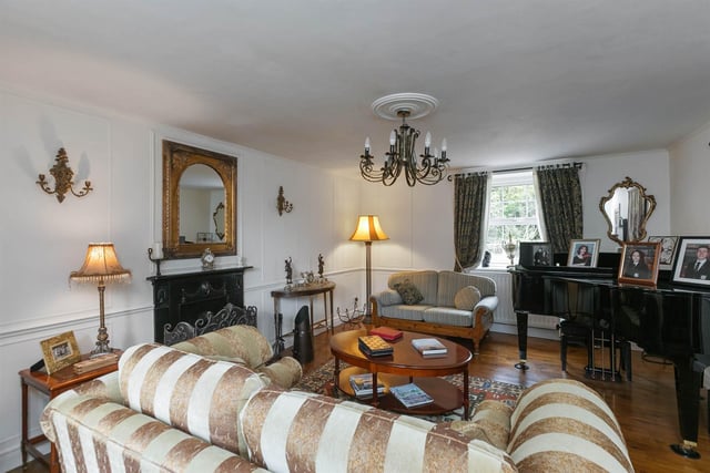 Living room with solid wood floor, corniced rose, cast iron fireplace with tiled hearth, and wood panelled walls.