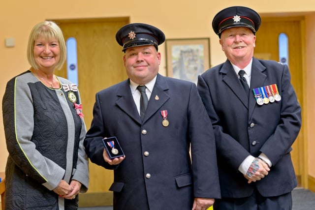 Firefighter Paul Crozier receives his medal from Deputy Lieutenant for Co Antrim, Mrs Jackie Stewart MBE. Also included is Watch Commander Brian Smith.