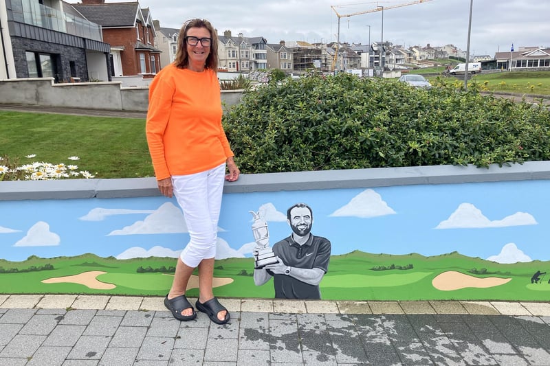 Maureen Davidson pictured beside the completed golfing greats mural, now featuring Open winner Scottie Scheffler.