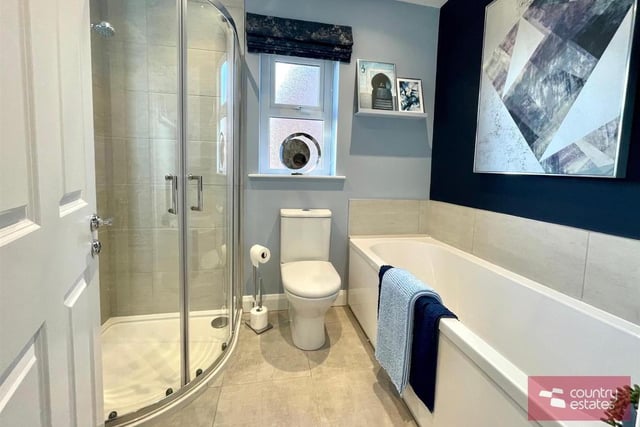 Family bathroom comprising quarter rounded fully tiled shower cubicle, modern vanity unit with monobloc tap, button flush WC, and panelled bath with tiled splash back.