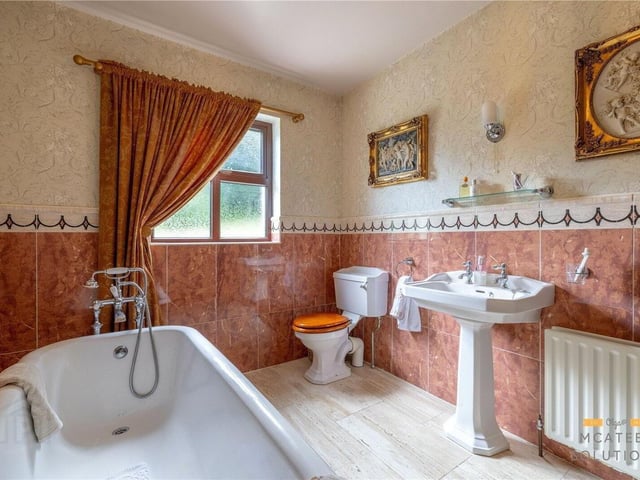Elegant three-piece traditional bathroom with 1/2 tiled walls and flooring including freestanding bath.