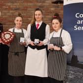 The winners from South Eastern Regional College, Nadia Rainey, Eimer McCarthy and Erin Horner, receive their gold medals from Lady Mary Peters.