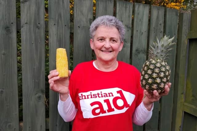 Lilian Edgar holds up a corn cob and pineapple, symbolising the work of a Christian Aid funded project which is supporting farmers in Guatemala’s ‘Dry Corridor’ to survive the climate crisis by helping corn crops to withstand drought and by introducing pineapple which tolerates drought well.  CREDIT CHRISTIAN AID