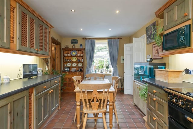 Kitchen with quarry tiled floor, range of high and low level units, Rangemaster double oven, and Belfast sink with granite worktops, as well as an integrated dishwasher and Bosch fridge.