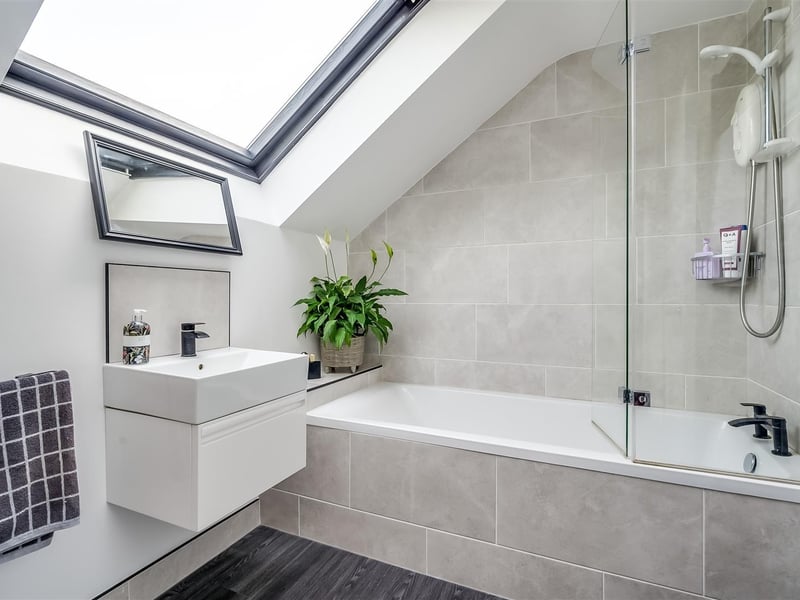 Deluxe bathroom with contemporary, white, three piece suite comprising tile encased bath, floating vanity unit and concealed cistern WC.