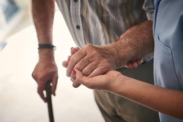 Female nurse supporting senior man to walk. Credit: Dean Mitchell/Getty Images