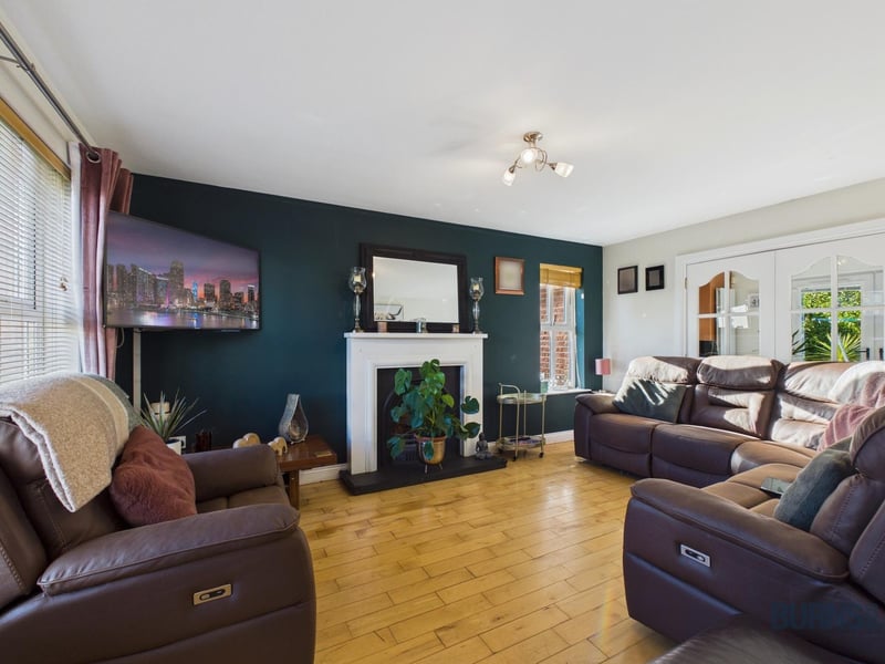 The lounge features an attractive fireplace, with doors leading through to the kitchen area.