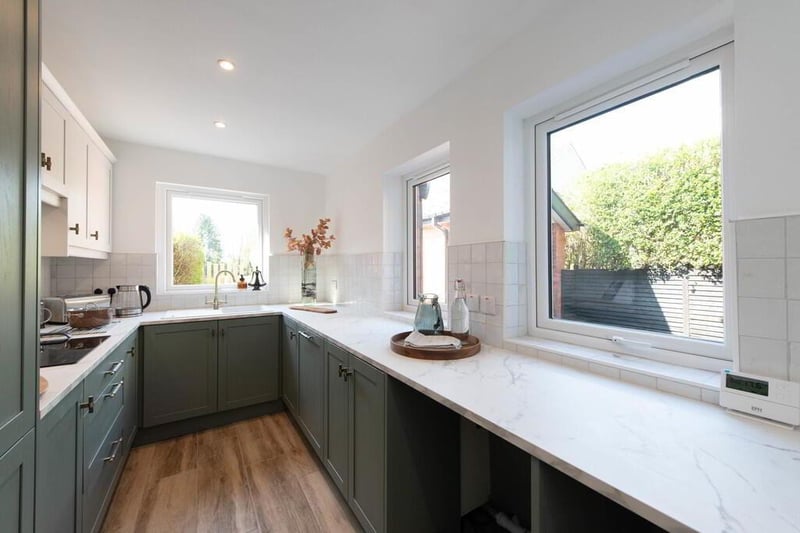 Modern fitted kitchen with range of high and low level units, laminate worksurfaces, modern sink unit with mixer taps, inlaid hob unit, extractor fan, double oven, fridge freezer, plumbed for dishwasher, ceramic tiled flooring, downlighters, and modern radiator.