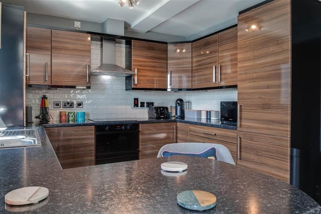 Kitchen with built-in high gloss walnut effect units and laminate worktops.