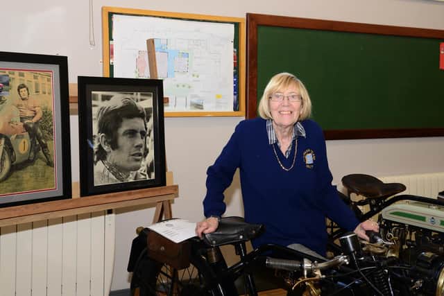 Chief organiser Joan Crawford posing beside photos of her favourite rider Gaicomo (Ago) Agostini supplied by Cecil Smith