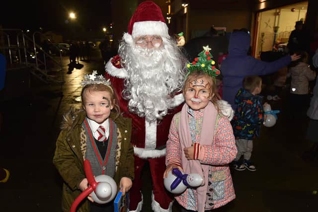 Posing happily with Santa at the Christmas lights switch on at the Mayfair Business Centre, Garvaghy Road, are Annie Cooney (5) and Ada Hawes (6). PT50-259.