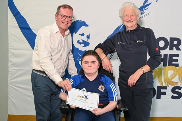 Glengormley powerchair football player Sean McKinney receiving his award certificate from Barry Funston and Lady Mary Peters. Sean is a member of the Northern Ireland Powerchair football team. Photo submitted by Mary Peters Trust