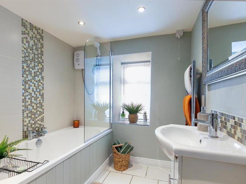 Modern bathroom with white three piece suite comprising panelled bath, vanity unit and WC.