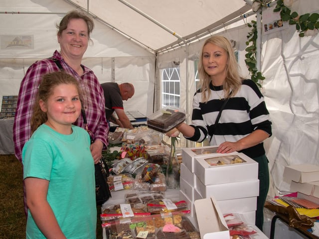 Pictured at the tray-bakes stall at the Drumcree Parish Garden Fete are from left, Darcie Brown (8), mum, Lellie and stallholder, Clara McGee.PT23-220.